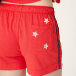 Red shorts with white star details and elastic waistband, modeled from back view
