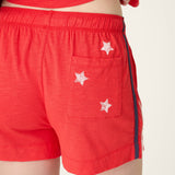 Red shorts with white star details and elastic waistband, modeled from back view