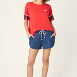 Woman wearing red short sleeve top with star logo and navy striped sleeves