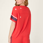 Woman wearing red short sleeve top with white stars and navy stripe details