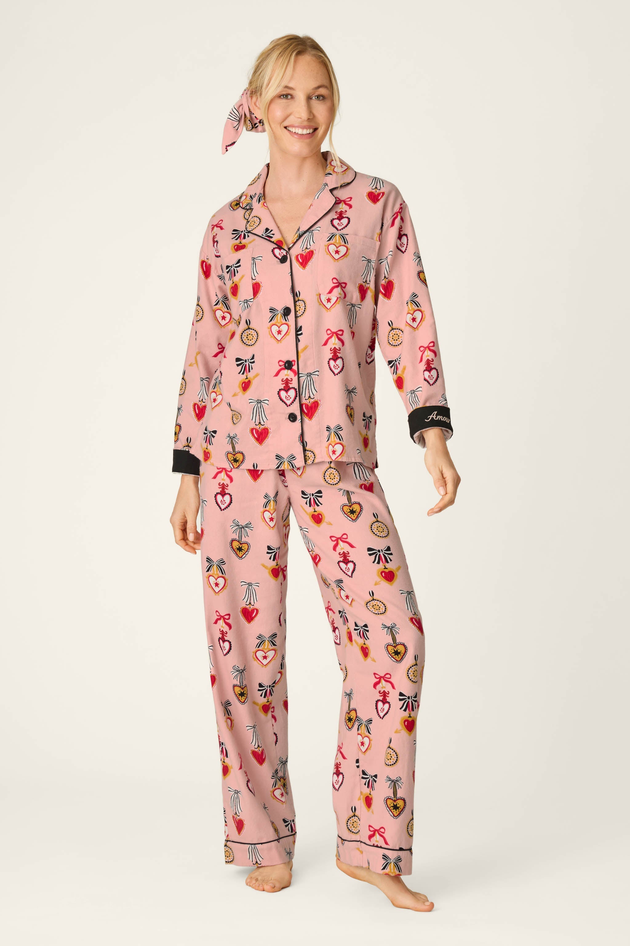Woman wearing PJ Salvage Love Lockets pink flannel pajama set with matching hair tie