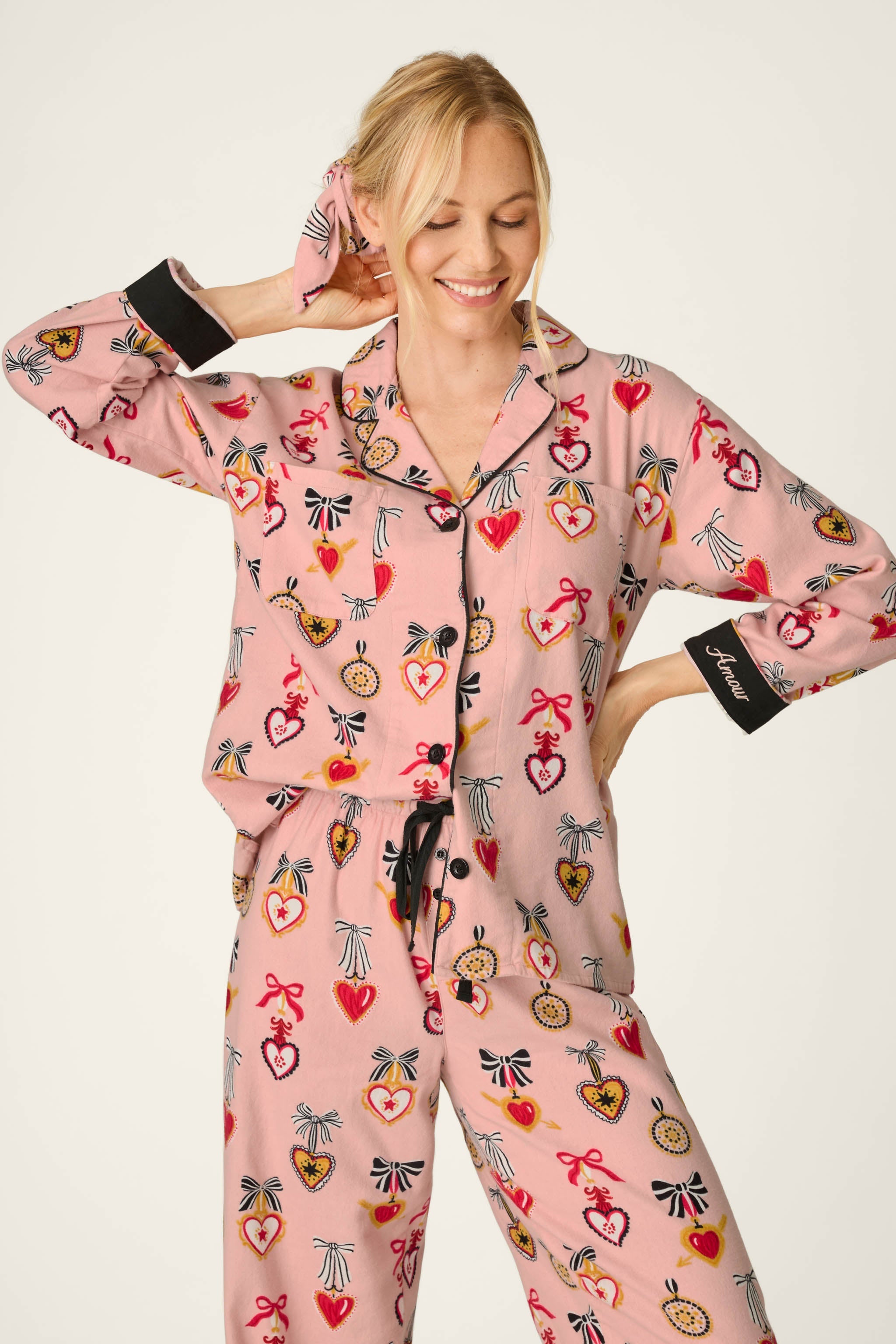 Woman wearing PJ Salvage Love Lockets pink flannel pajama set with heart and bow print
