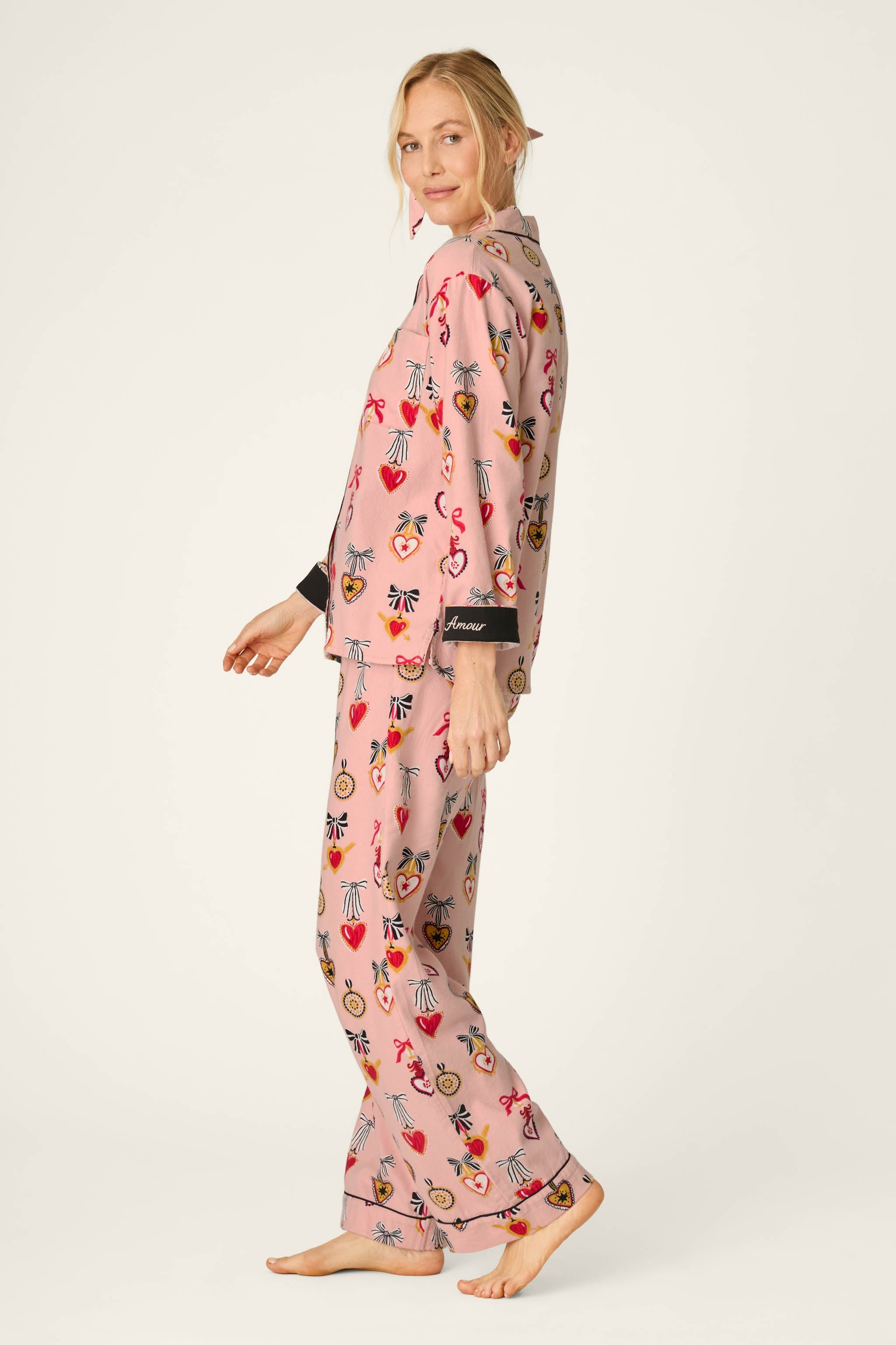 Woman wearing PJ Salvage Love Lockets pink long sleeve flannel pajama set with hearts and bows print