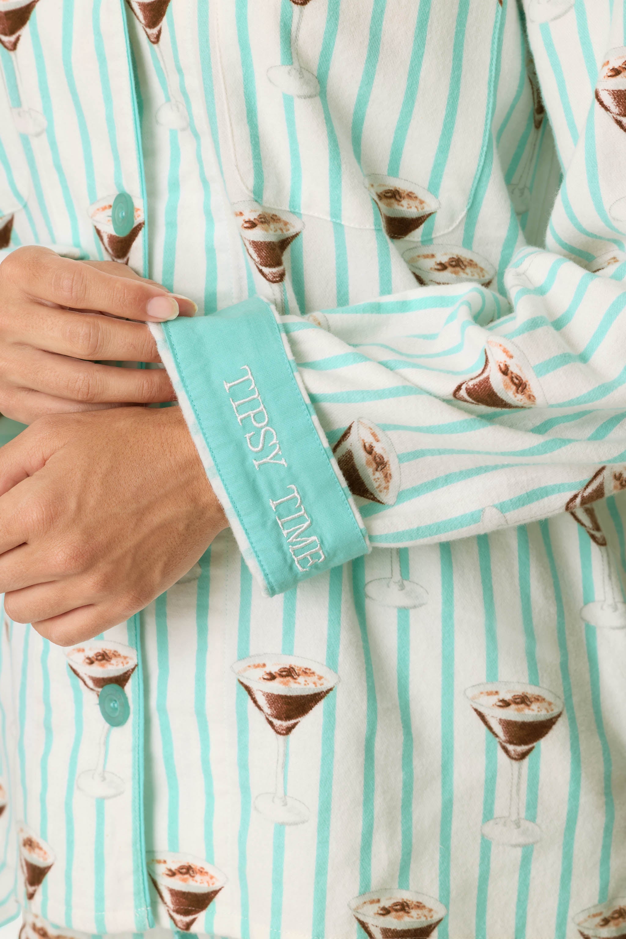 Close-up of PJ Salvage flannel pajama cuff embroidered with Tipsy Time text, espresso martini print