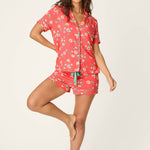 Woman wearing coral floral pajama set with button-up shirt and shorts