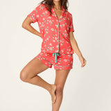 Woman wearing coral floral pajama set with button-up shirt and shorts