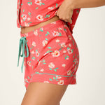 Woman wearing coral floral print pajama shorts and matching top set