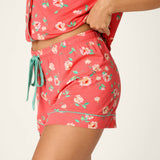 Woman wearing coral floral print pajama shorts and matching top set