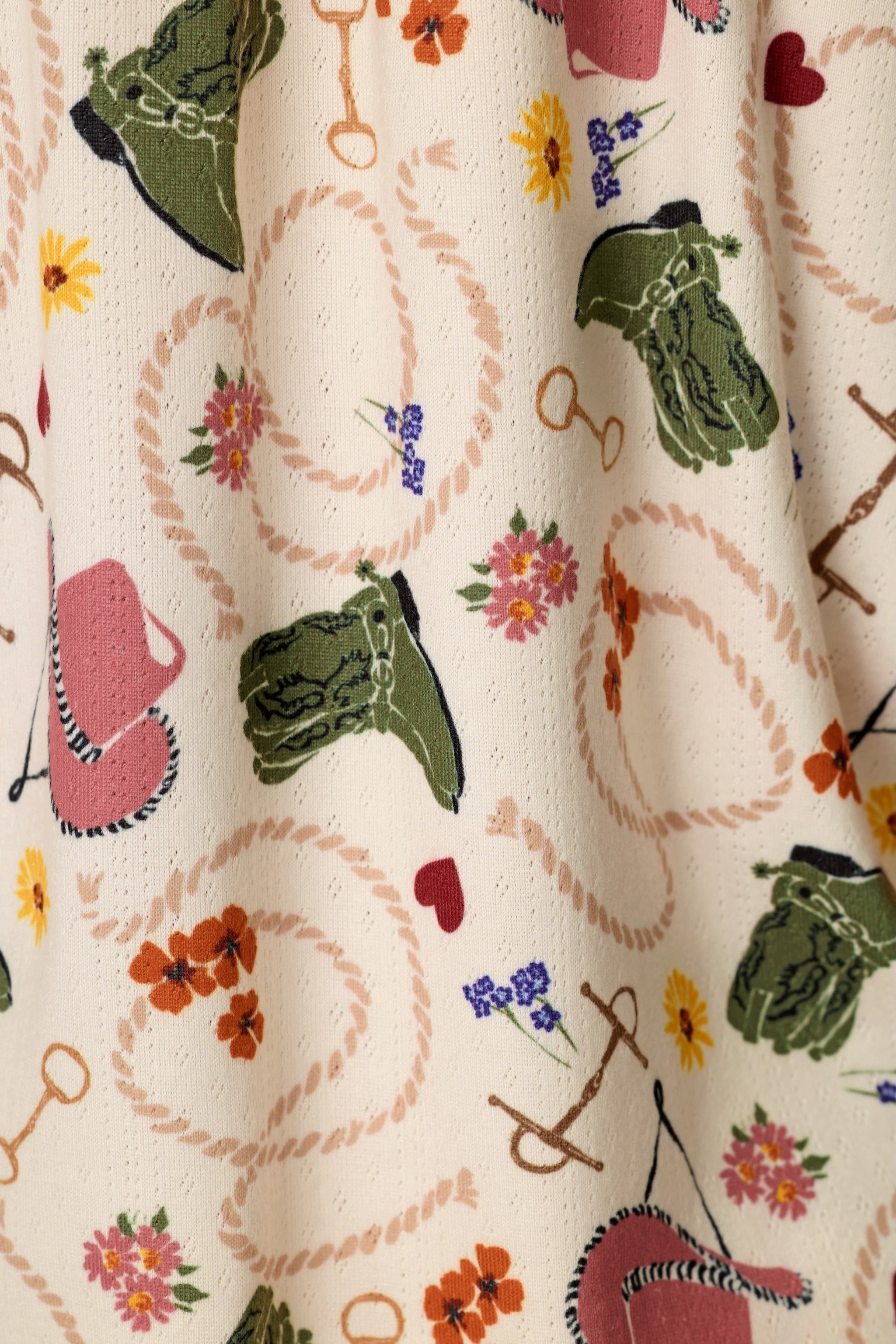 Close-up of PJ Salvage Saddle Up Western print fabric in nude with colorful western motifs