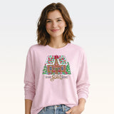 Woman wearing light pink long sleeve sweatshirt with gingerbread house Home Sweet Home graphic