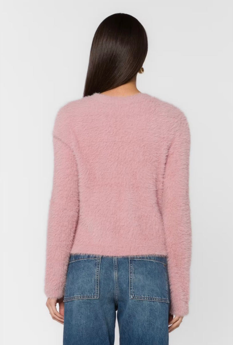 Back view of woman wearing fluffy mauve pink cropped sweater with blue jeans