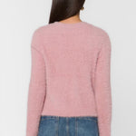 Back view of woman wearing fluffy mauve pink cropped sweater with blue jeans