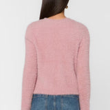 Back view of woman wearing fluffy mauve pink cropped sweater with blue jeans