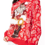Woman wearing red paisley print cowboy Santa sweater with 3D pom detail