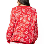 Back view of red and white paisley print knit sweater on female model with white skirt