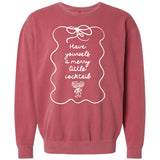 Mauve or dusty rose pigment-dyed crewneck sweatshirt featuring a whimsical white line graphic framing the text "Have yourself a merry little cocktail" above a drawing of a decorated martini glass.