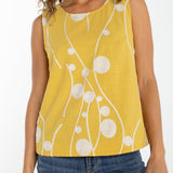 Woman wearing yellow sleeveless top with cream embroidered circles and curved lines