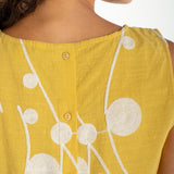 Yellow sleeveless top with cream embroidered circular botanical design and button back closure