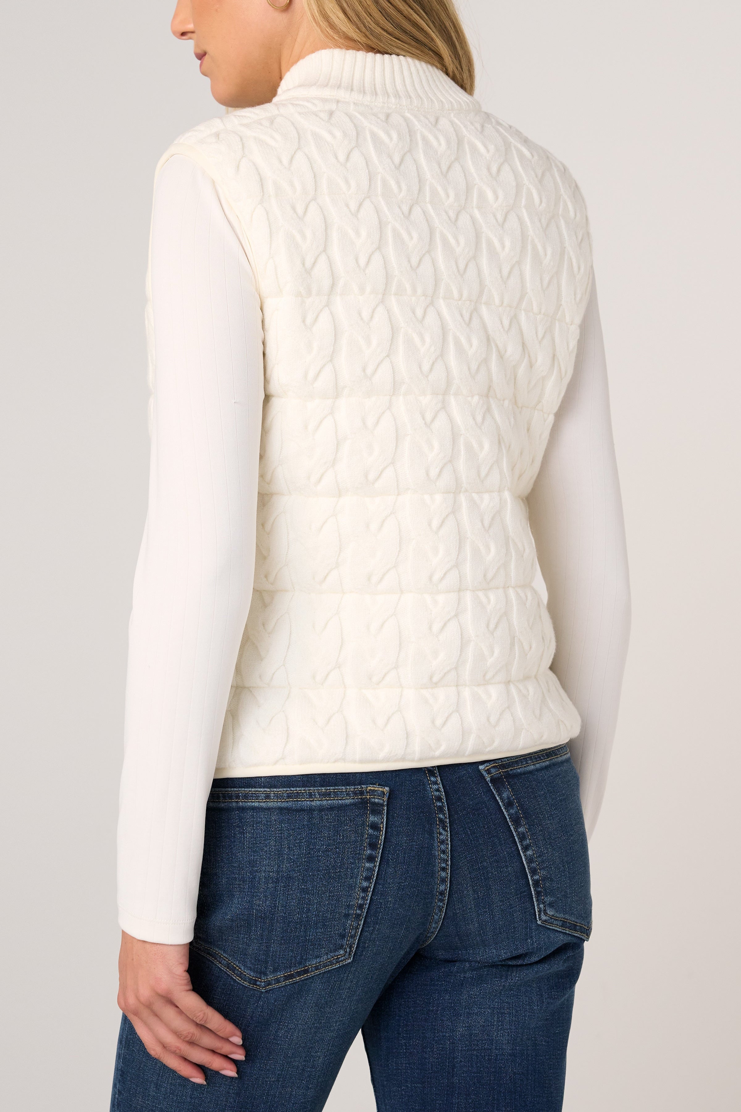 Back view of Liverpool cream cable-knit quilted sweater vest over white long-sleeve top