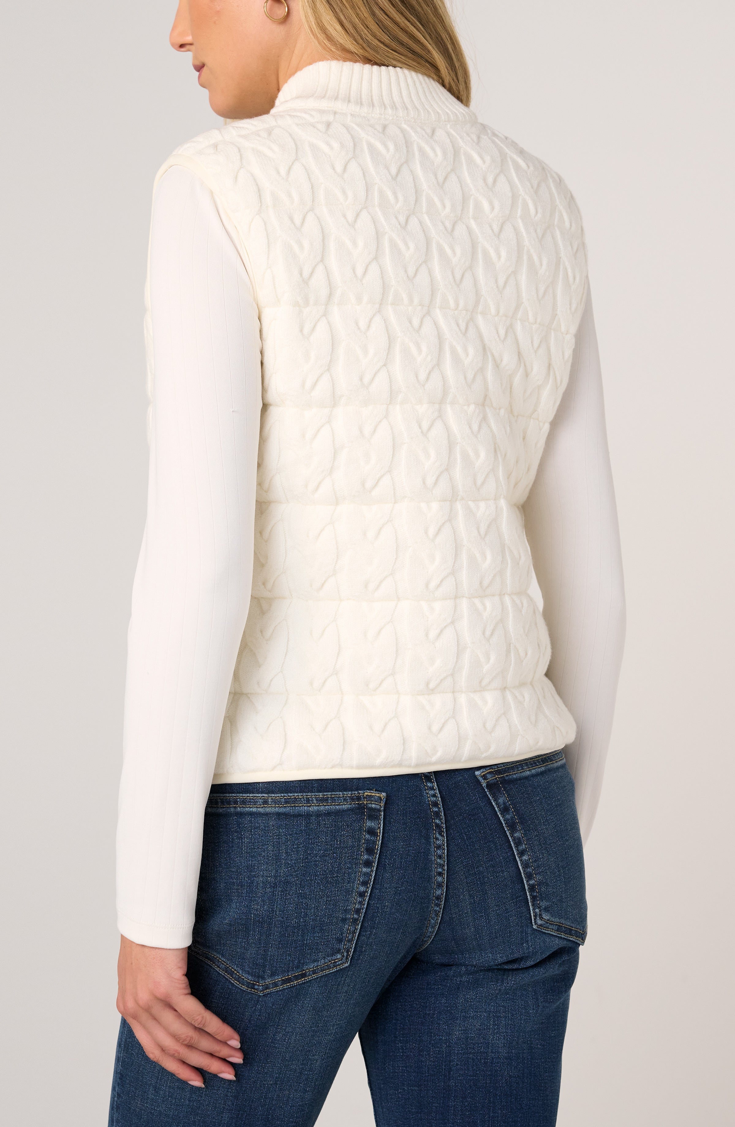 Back view of Liverpool cream cable-knit quilted sweater vest over white long-sleeve top
