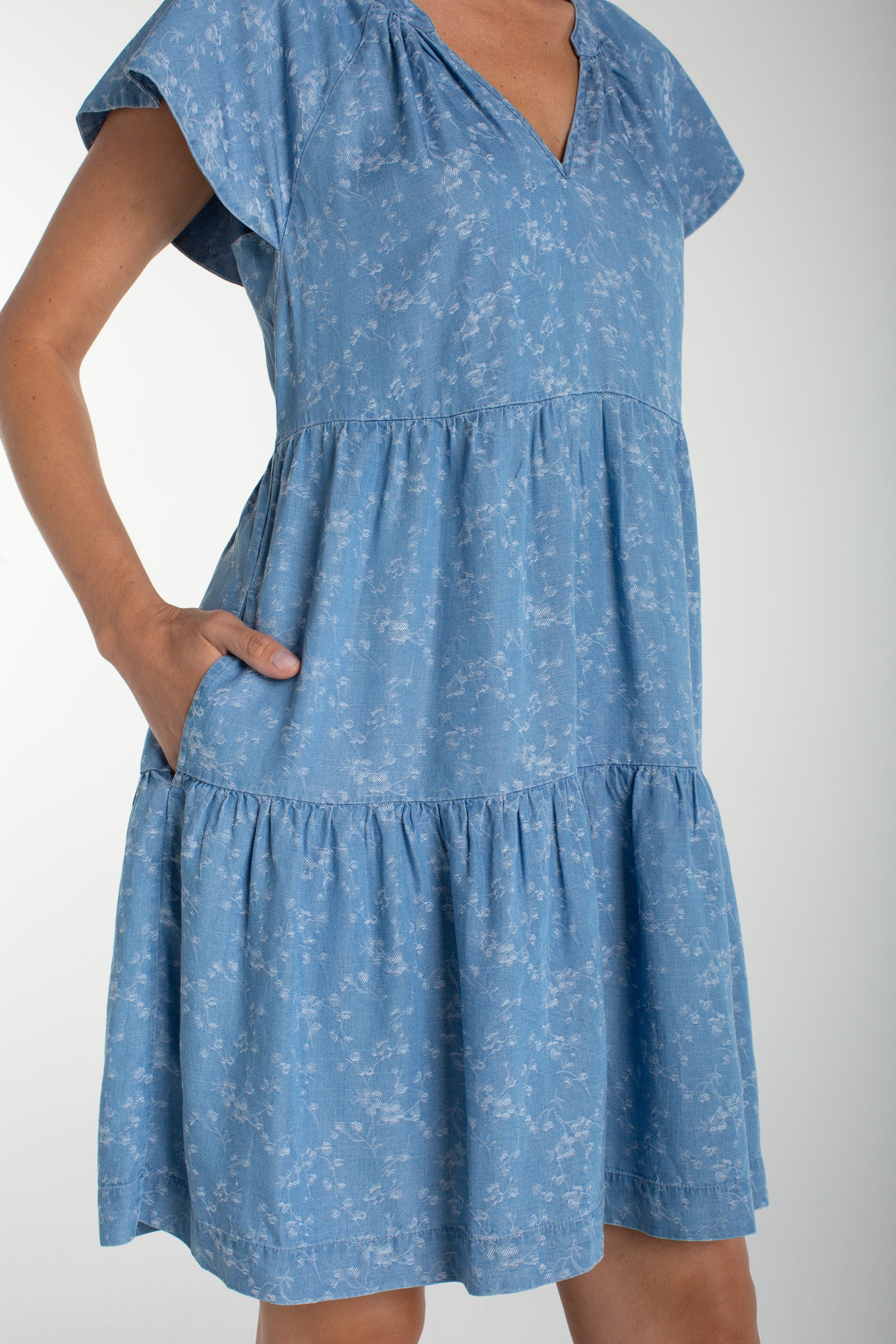 Liverpool Los Angeles, denim dress, floral mini dress, tiered dress with pockets, indigo roses, summer flutter sleeve dress, light wash denim dress, feminine casual style. at ooh la la! in 
Grapevine TX 76051