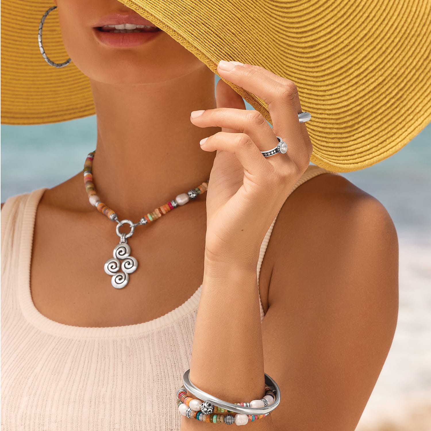 Brighton Vertigo Hues stretch bracelet with multicolor beads, pearls, and silver bangle on model at beach